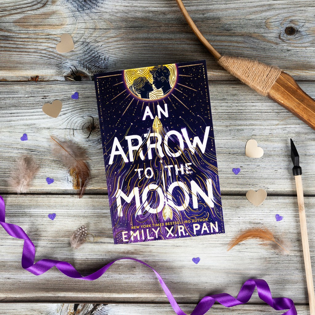 An Arrow to the Moon paperback shown on wooden background with bow and arrow