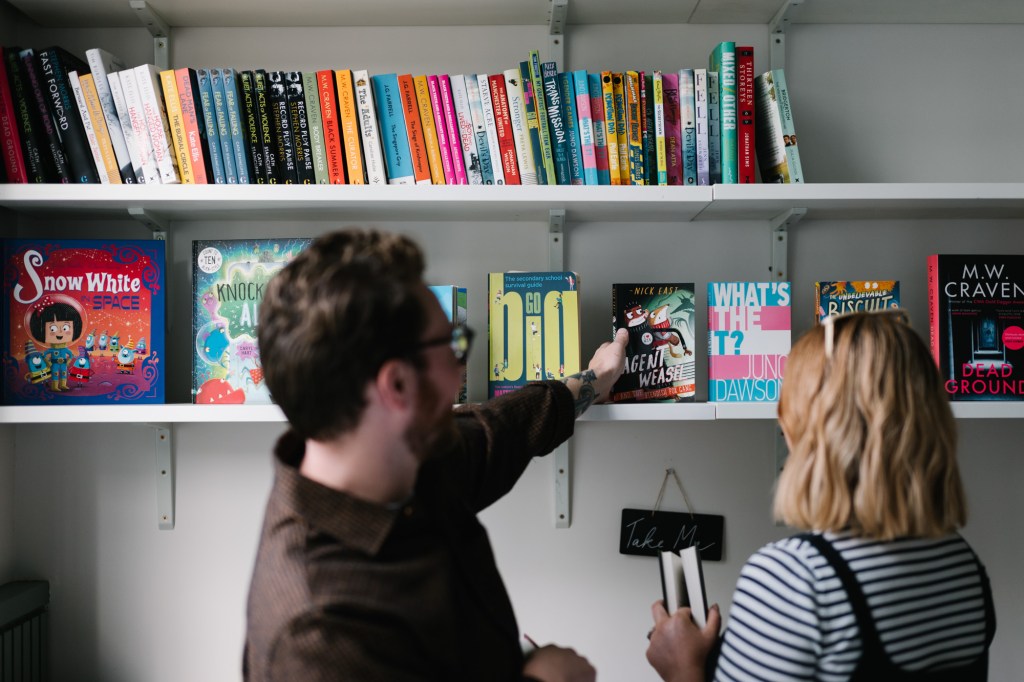 Colleagues browsing books on a bookshelf.