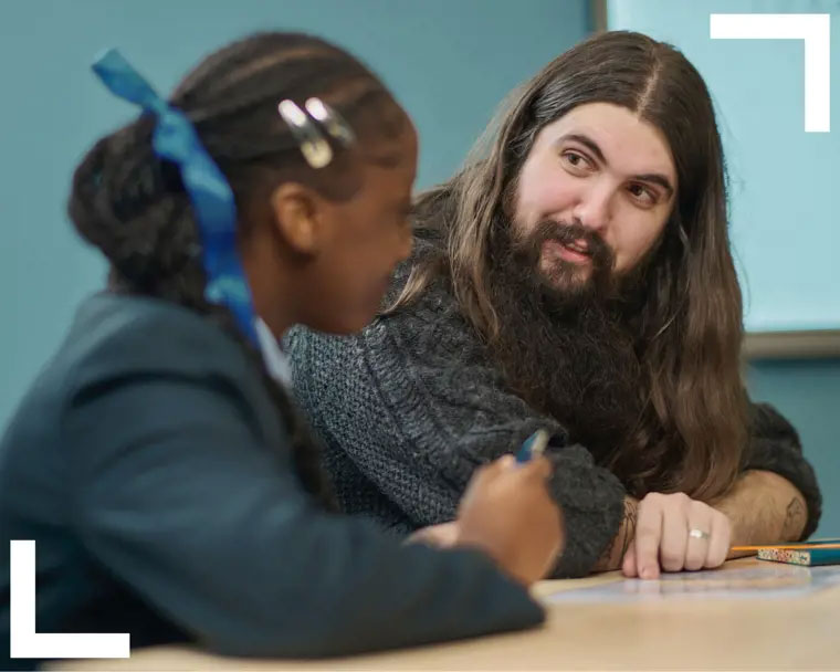 Teacher going through a work sheet one-on-one with pupil at desk
