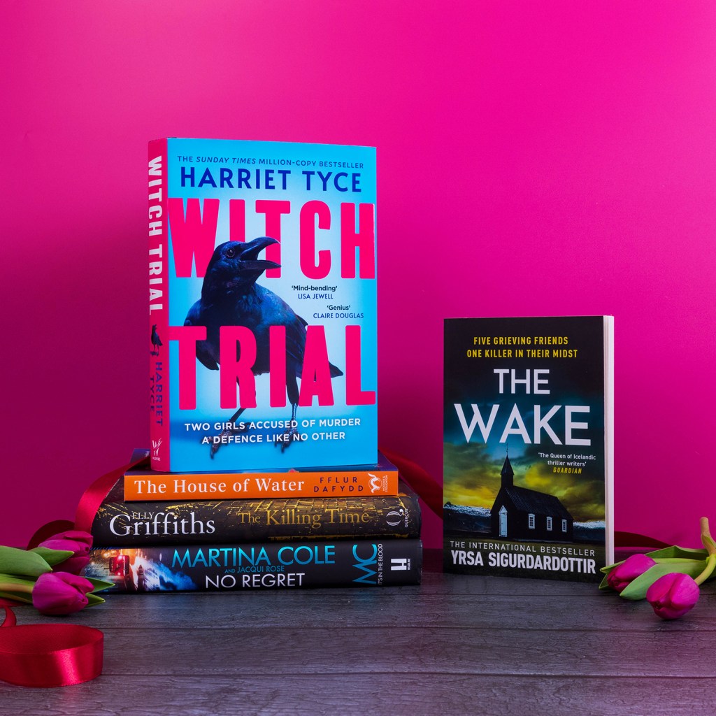 Photograph of five books, surrounded by pink flowers and ribbon. The books are: Witch Trial by Harriet Tyce, The House of Water by Fflur Dafydd, The Killing Time by Elly Griffiths, No Regret by Martina Cole, The Wake by Yrsa Sigurdardottir